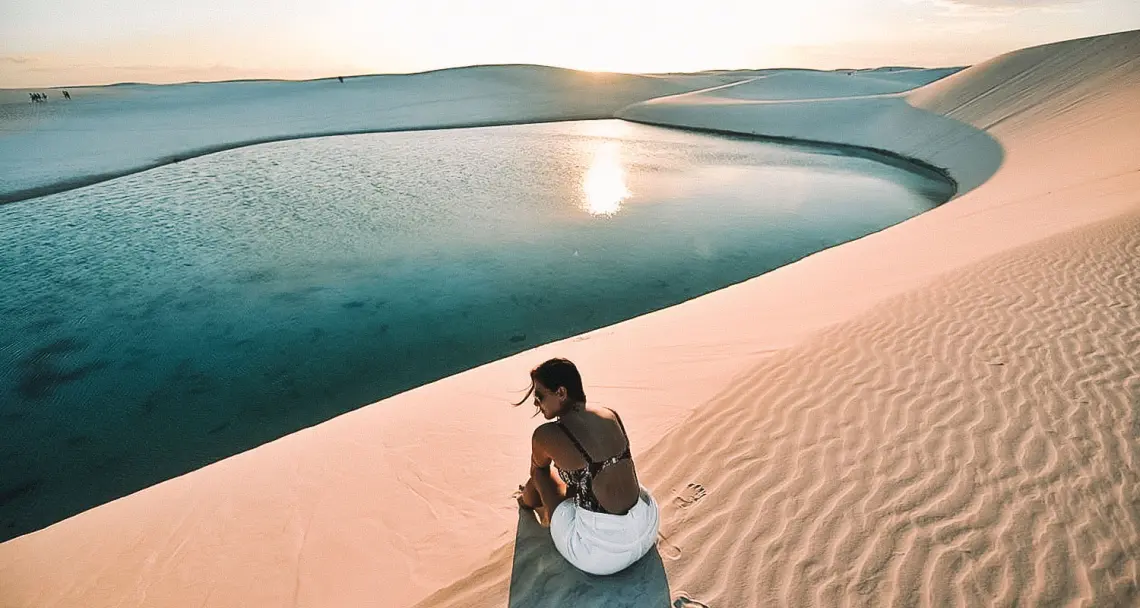 Viajante diante de uma lagoa entre as dunas dos Lençóis Maranhenses